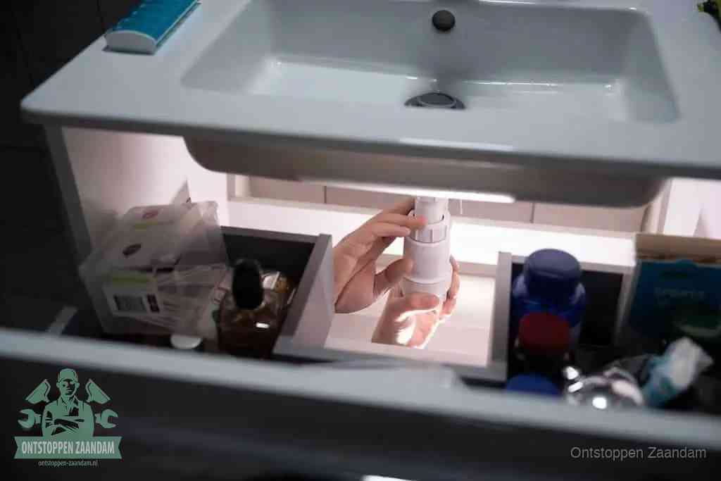 Een pompfles met zeep boven een wastafel, de heet water en afwasmiddel-methode om een vetprop in de afvoer los te maken in Zaandam