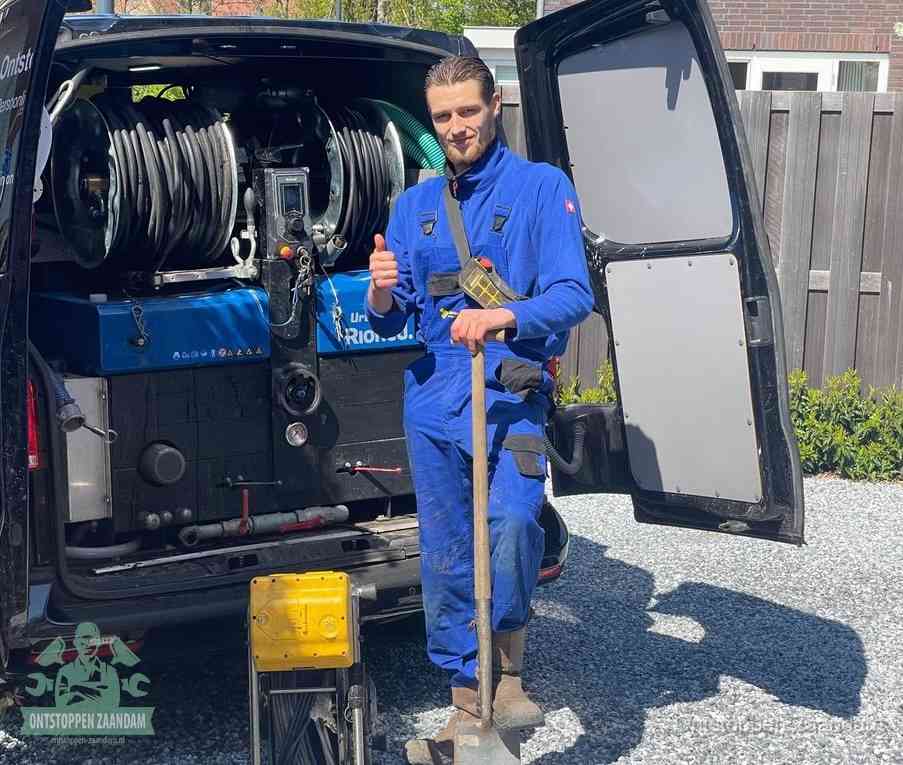 Een tevreden monteur met opgestoken duim naast de bestelbus, slim ingrijpen bespaart kosten bij een verstopte afvoer in Zaandam