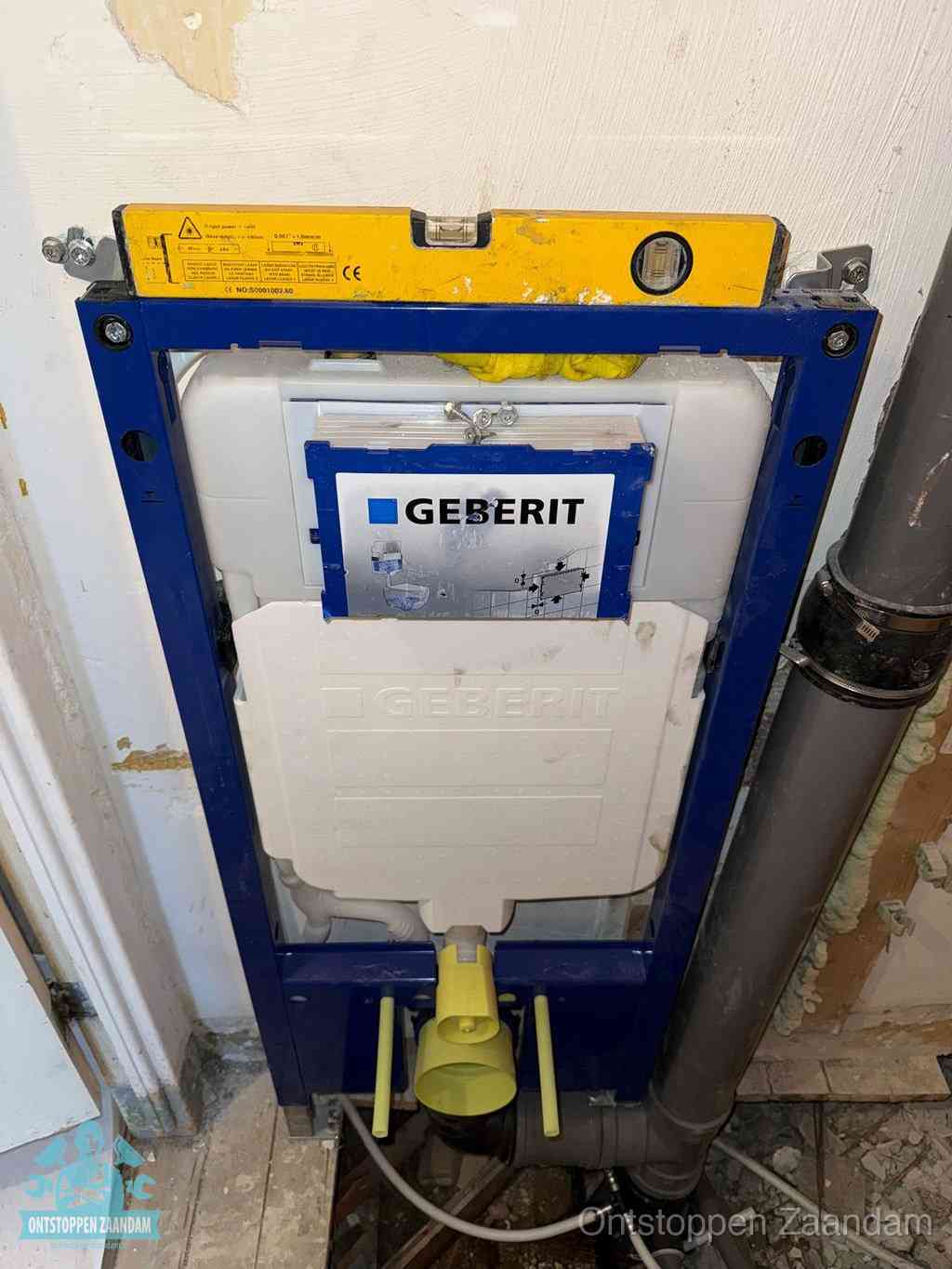 Een Geberit inbouwreservoir met frame voor een hangtoilet tegen de wand, met de afvoerbocht naar de vloer, kenmerkend voor een verstopt hangtoilet in Zaandam