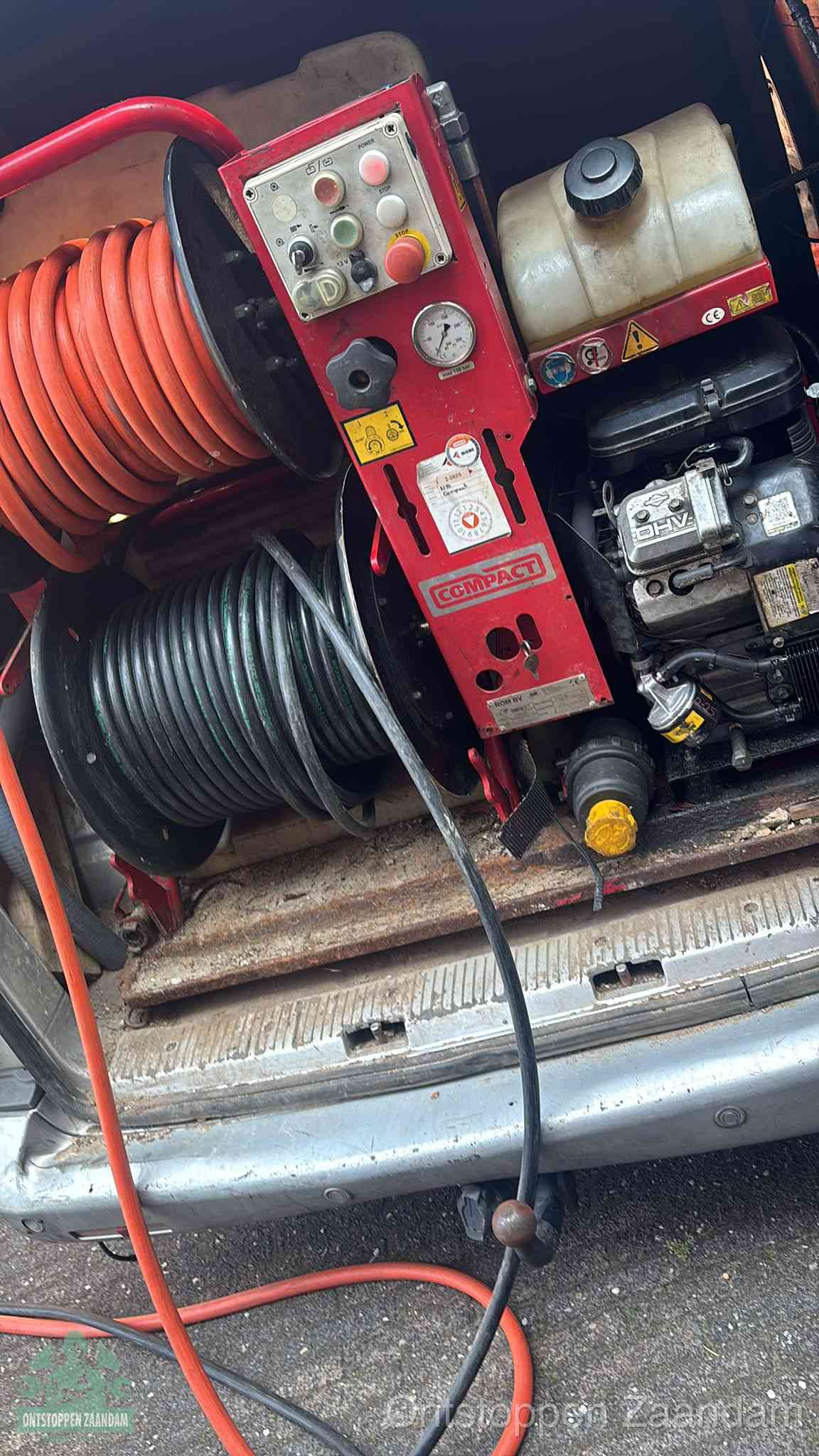 Een rood hogedruk-rioolreinigingstoestel in de laadbak van de bedrijfsbus, apparatuur voor een hardnekkige afvoerverstopping in Zaandam