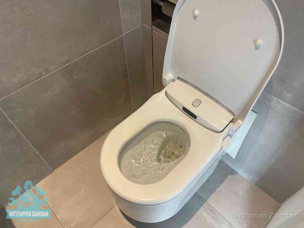 Een toiletpot vol troebel water met drijvend papier en restanten, de meest voorkomende oorzaak van een verstopte wc in Zaandam