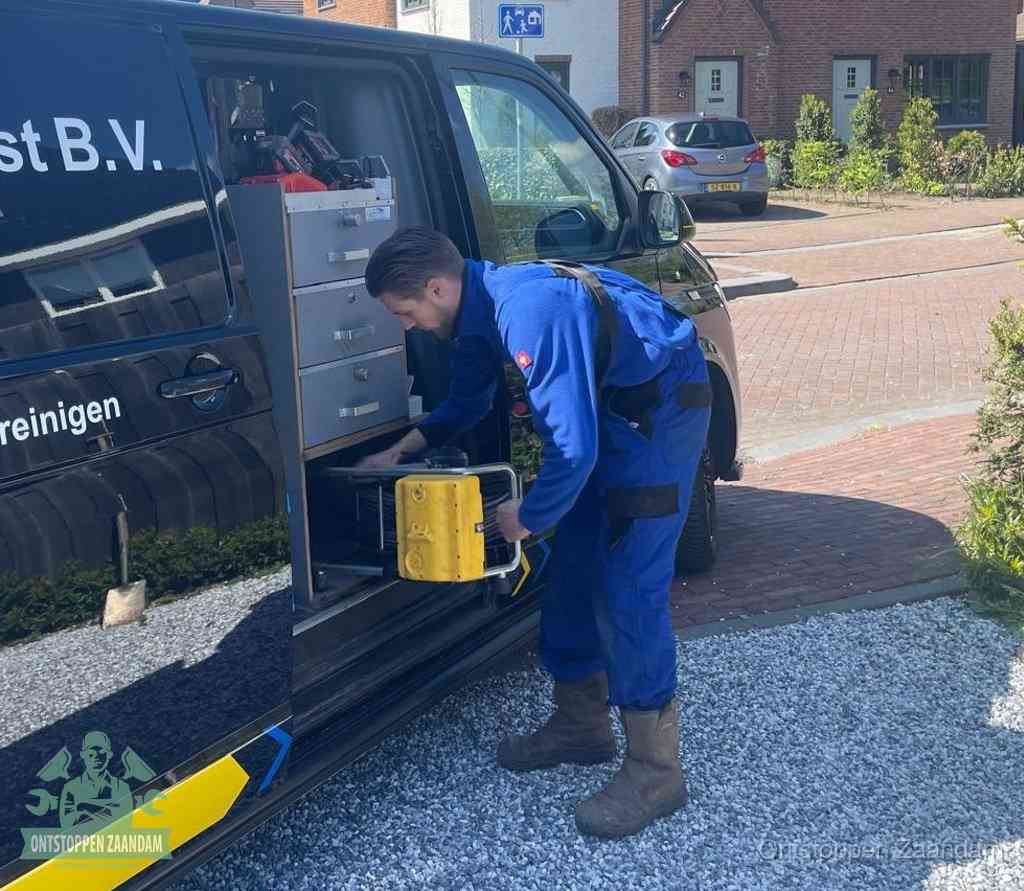 Een monteur pakt buiten op de oprit gereedschap uit de bedrijfsbus, het moment om een professional in te schakelen voor een verstopte afvoer in Zaandam