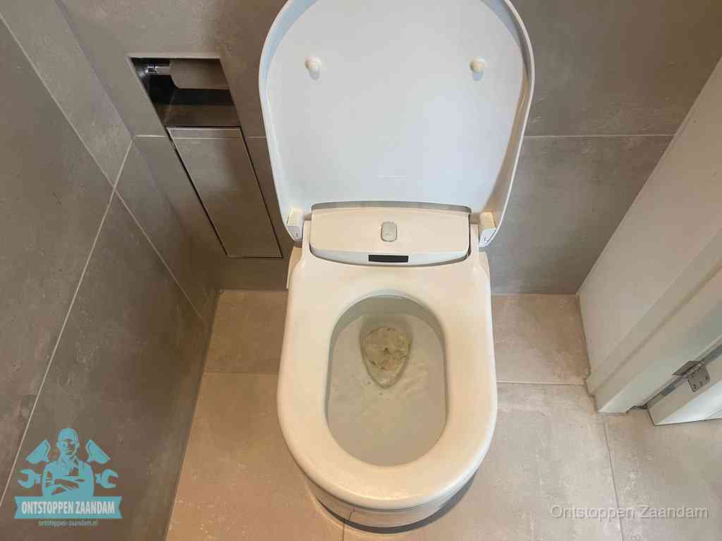 Een wit hangtoilet waarin een prop wc-papier op het water blijft drijven, een duidelijk signaal van een verstopte wc in Zaandam