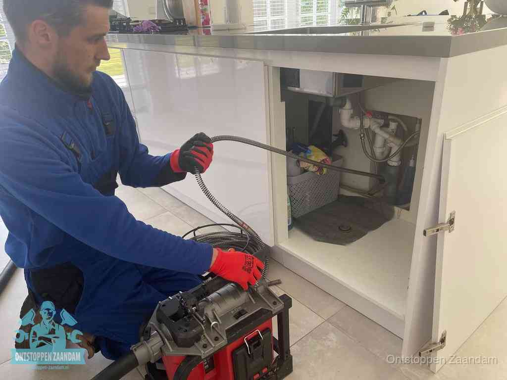 Een monteur reinigt de keukenafvoer grondig met een veermachine om terugkerende gootsteenverstoppingen te voorkomen in Zaandam