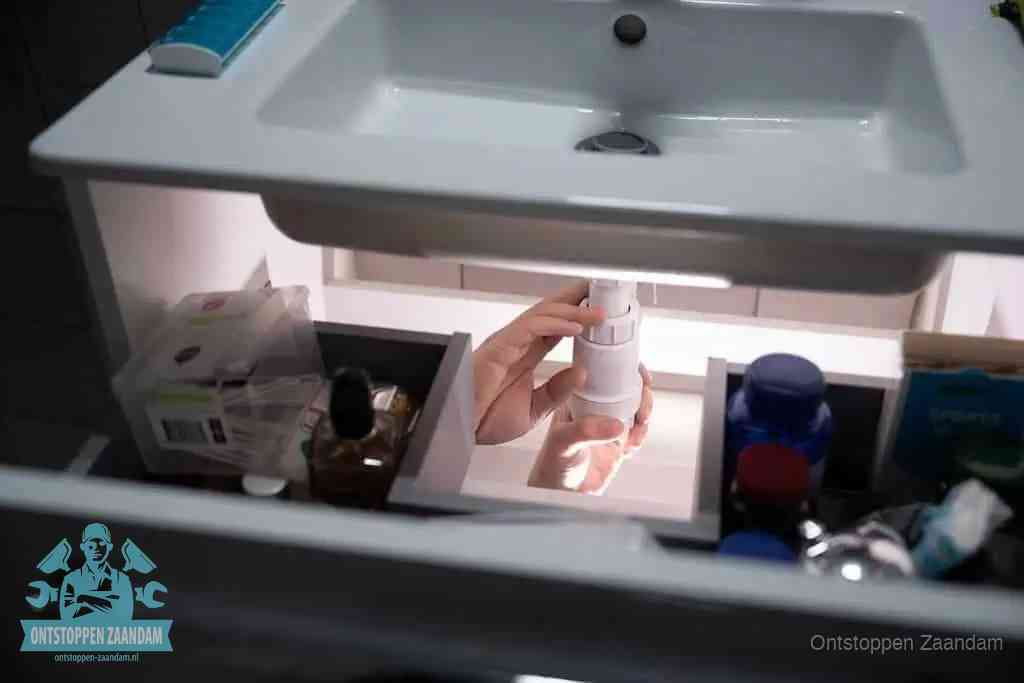 Een pompfles met zeep boven een wastafel in de toiletruimte, de warm water en afwasmiddel-methode om de wc te ontstoppen in Zaandam