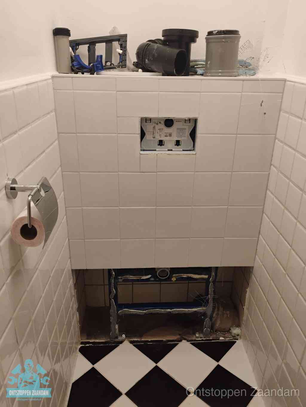 Een toiletruimte waar het hangtoilet en de inbouwreservoir-onderdelen zijn vrijgelegd voor onderhoud, periodiek nazicht voorkomt een wc-verstopping in Zaandam