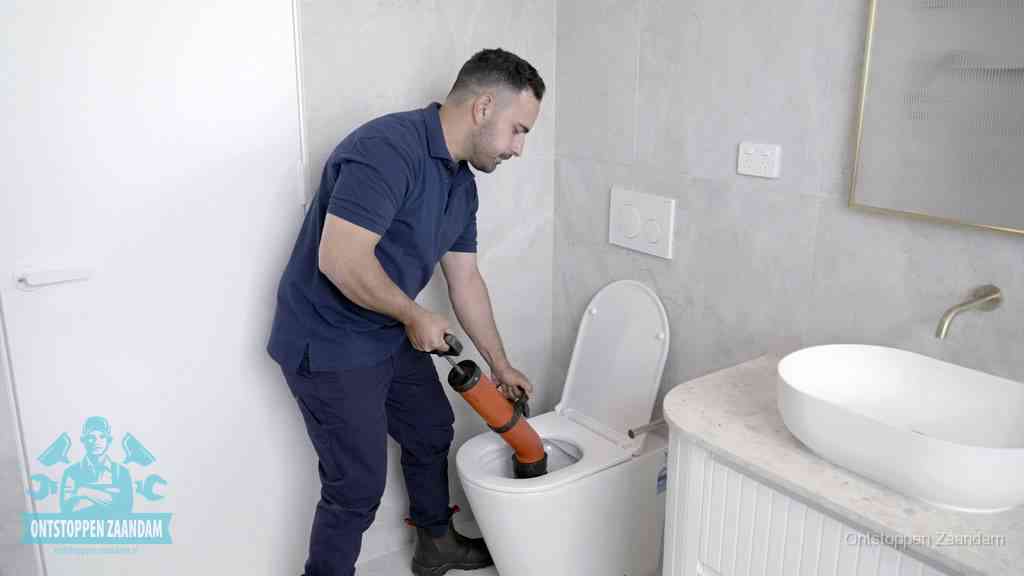 Een monteur gebruikt een handmatige perspomp (toiletontstopper) op een wandcloset tijdens het professioneel wc ontstoppen in Zaandam